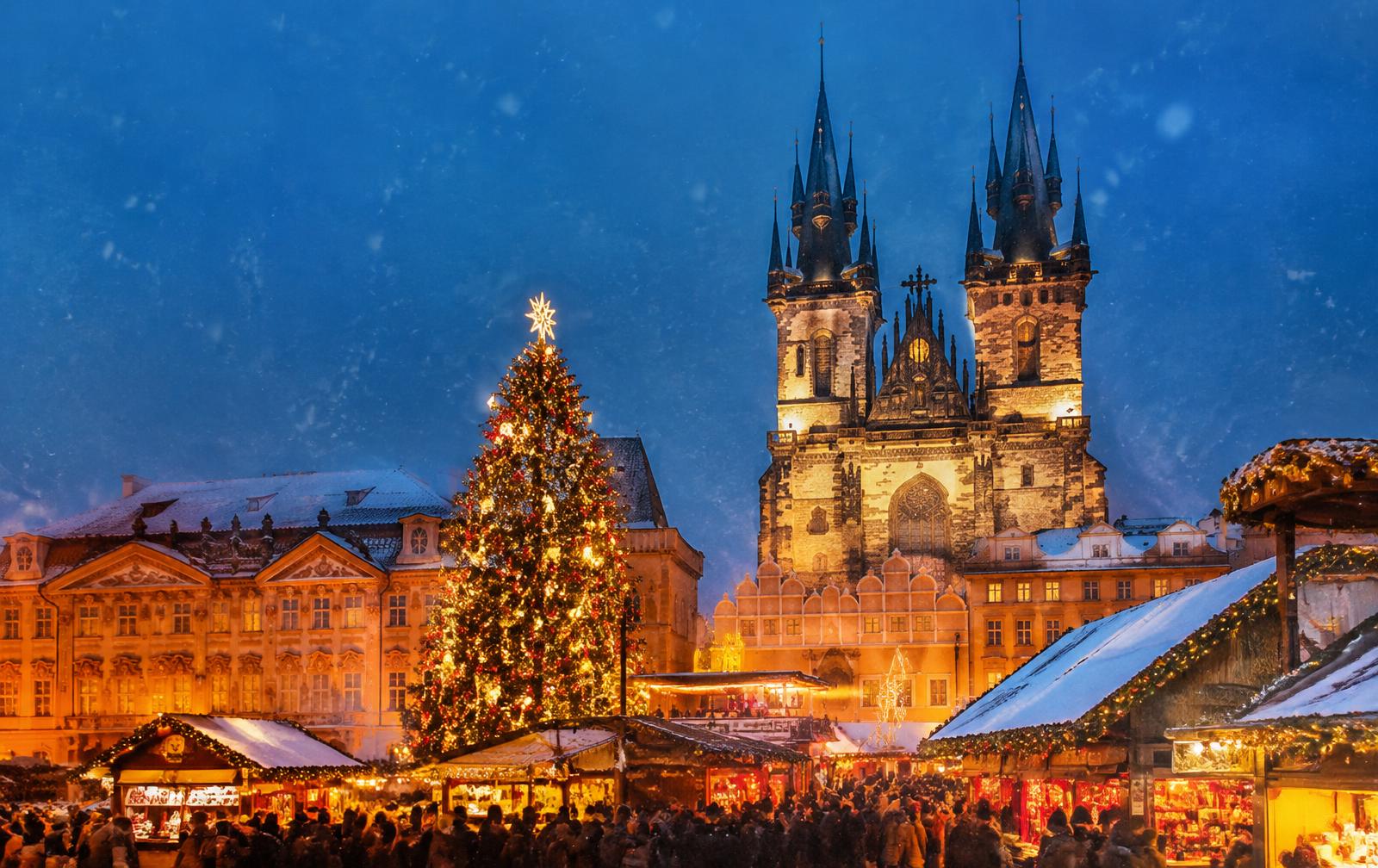 Old Town Square Christmas market in Prague at night with a giant Christmas tree and Týn Church